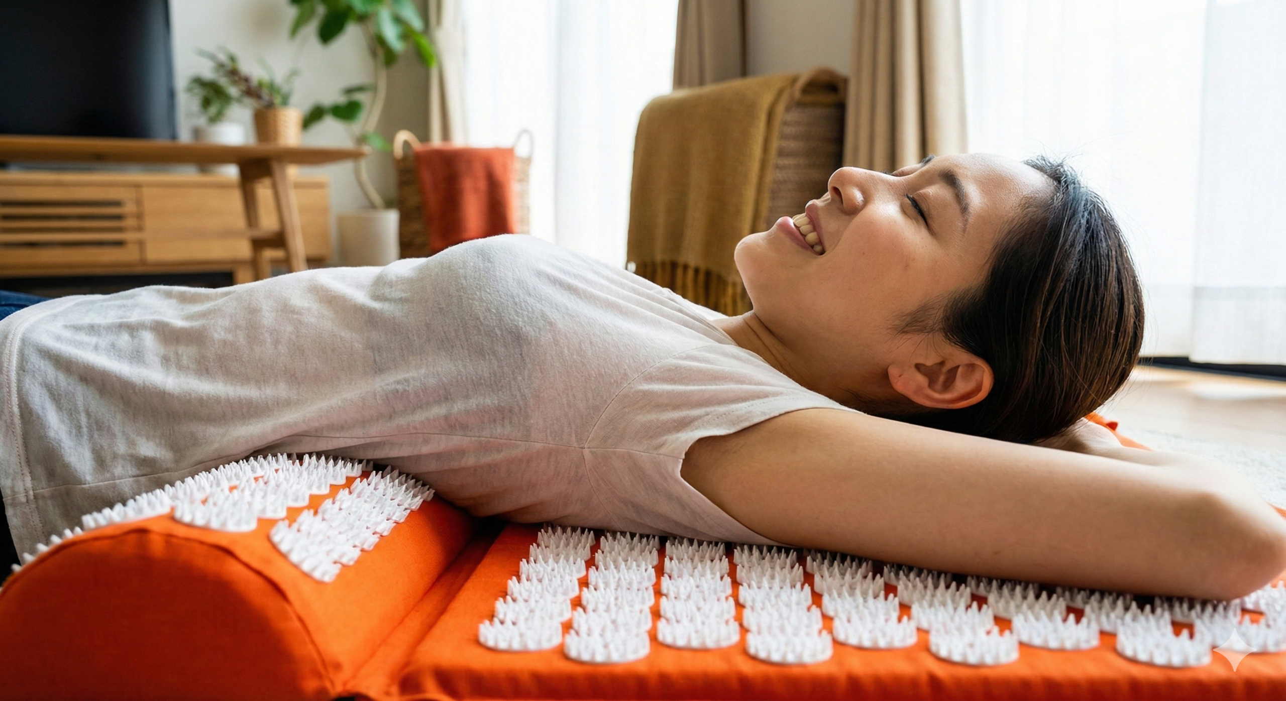 指圧マットでくつろぐ若い日本人女性 オレンジ色の指圧マットの上で、若い日本人女性が目を閉じて微笑みながら横たわっている