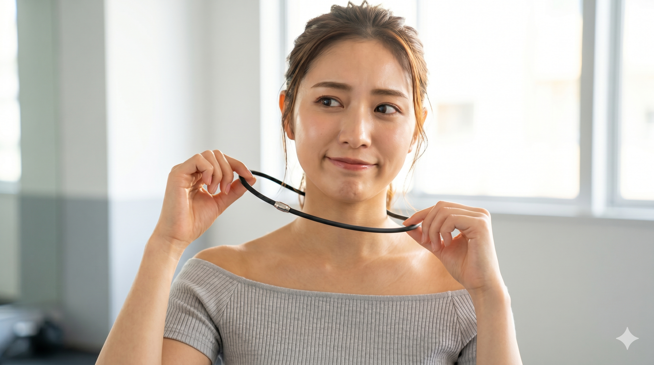 磁気ネックレスを疑いながら試すジムの日本人女性 ジムの明るい背景で、疑わしげな表情を浮かべた日本人女性が、両手で黒い磁気ネックレスを首につけようとしている。